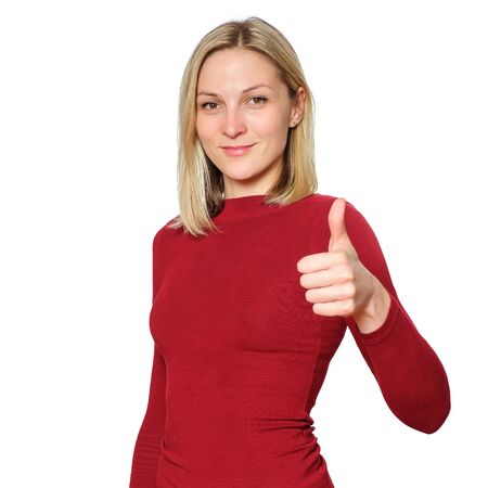 Young blonde caucasian woman wears informal warm red sweater showing thumb up isolated on white backgroundの写真素材