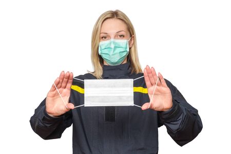 Portrait young caucasian female lifeguard in uniform and surgical mask shows protective mask in outstretched hands. virus outbreak precautions. isolated on white, selective focusの写真素材