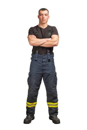 Young firefighter with folded arms wearing black t-shirt and fireproof pants with suspenders isolated on white backgroundの写真素材