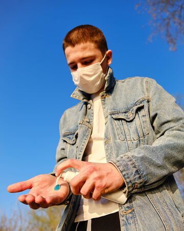 Young boy using alcohol antiseptic gel in sanitizer bottle for frequently cleaning hands and prevent infection coronavirus Covid-19 and other germs, bacteria and virusesの写真素材
