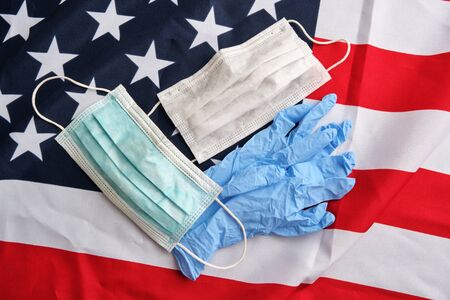 Used surgical protective masks and gloves on american flag background. Covid-19 quarantine. Flat lay, top viewの写真素材