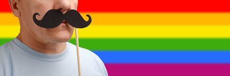 portrait caucasian man with fake mustache on stick in support of a gay pride to help people awareness lgbt rights. Close up viewの写真素材
