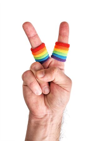 Male hand making the V sign with fingers wears wristbands painted as rainbow flag isolated on white backgroundの写真素材