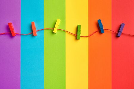 rainbow colored wooden clothespins on rope against lgbt flag background. Pride day concept, flat layの写真素材
