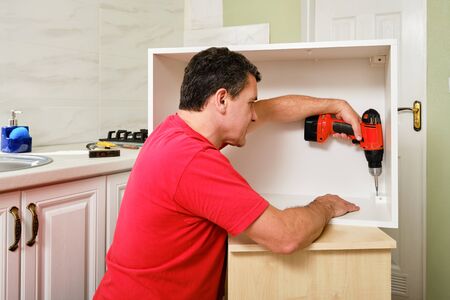 middle aged white man screwed the furniture fittings with cordless screwdriver.の写真素材
