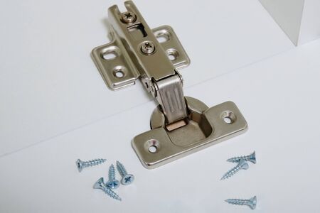 installation of furniture hinges in the new kitchen cabinet door or replace the hinges closeup.の写真素材