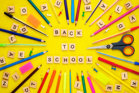 Wooden letters arranged in phrase back to school, pencils, felt-tip pens, pins, scissors and other...