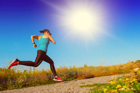 young white fitness woman runs up the countryside road. Copy space for textの写真素材