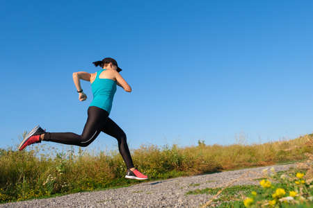 young caucasian fitness woman runs up the country road. Copy space for textの写真素材