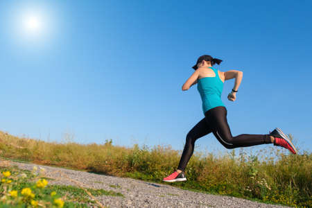 young white fitness woman runs up the countryside road. Copy space for textの写真素材