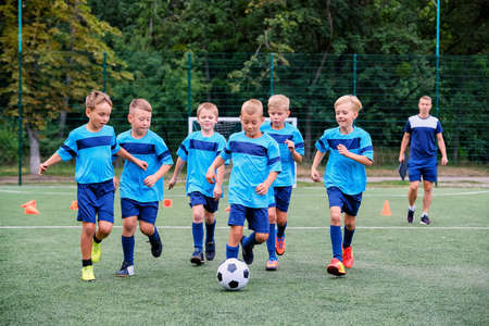 Kids running and kicking soccer ball on children football training sessionの写真素材