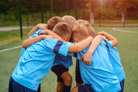 Kids football team embrace each other on football field before matchの写真素材