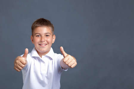 Handsome smiling caucasian boy gesturing with two thumbs upの写真素材