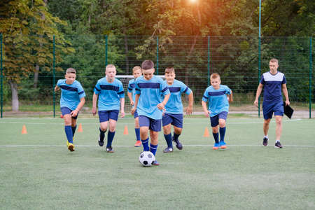 Children running and kicking soccer ball on football training sessionの写真素材