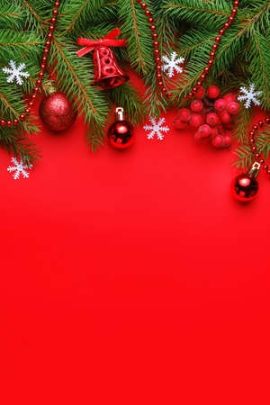 Top view Christmas composition with spruce branches and toys on red backgroundの写真素材