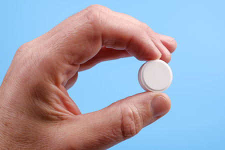 Big white tablet in mans hand on blue background. Close Up viewの写真素材