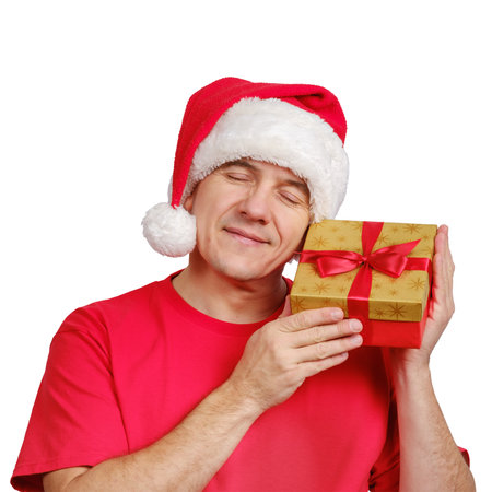 Middle-aged caucasian man in Santa hat receive Christmas gift, holds near his face and smiling with closed eyes isolated on white background.の写真素材