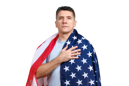 Handsome middle-aged man covered with American flag puts hand on his heart and looking at camera isolated on white background.の写真素材