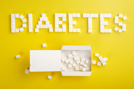 Word diabetes made from sugar cubes and an open pack of sugar cubes on a yellow background, copy space. Unhealthy food conceptの写真素材