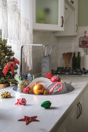 Christmas toys and unwashed dishes in kitchen sink after Christmas and New Year celebration in morning. Vertical orientation, selective focusの写真素材
