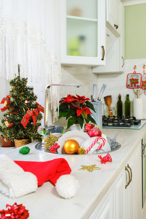 Christmas toys and unwashed dishes in kitchen sink, Santa hat after Christmas and New Year celebration in morning. Vertical orientation, selective focusの写真素材
