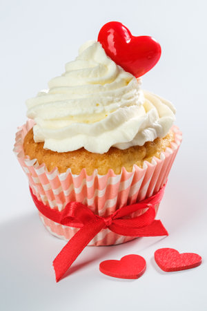 One valentines cupcake with heart shaped caramel candy on top on white background. Vertical orientationの写真素材