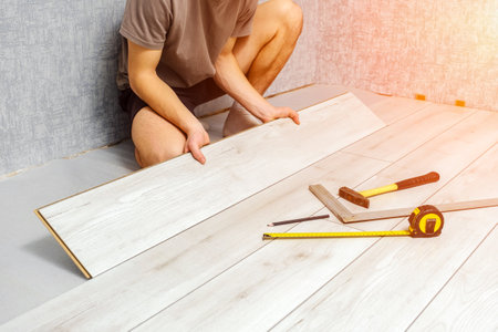 male hands is laying wooden panel of laminate floor indoors. Laminate flooring, copy spaceの写真素材