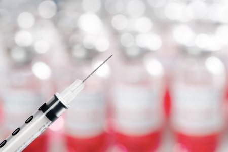 The needle of syringe closeup on blurred vaccine vials to fight the of Covid-19 SARS-CoV-2 coronavirus. Copy space for textの写真素材
