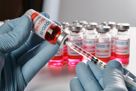 Doctors hand in blue protective gloves holds vaccine vial and fill syringe with coronavirus vaccine for injection. Vaccination against COVID-19 SARS-CoV-2 pandemic. Close-up viewの写真素材