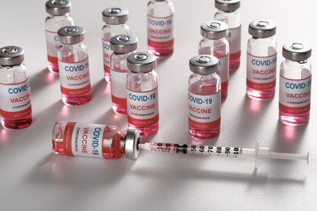 Syringe filling with COVID-19 vaccine on glass vials background, closeup. High quality photoの写真素材