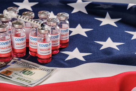 American flag, coronavirus vaccine vials, syringe and money for purchase or trading vaccine concept. Copy space for textの写真素材
