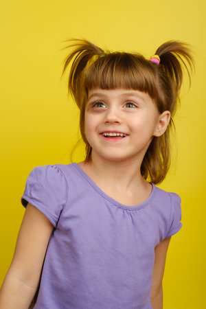 Portrait of smiling little caucasian girl with pigtails and bruise under the eye and looks away. Vertical orientationの写真素材