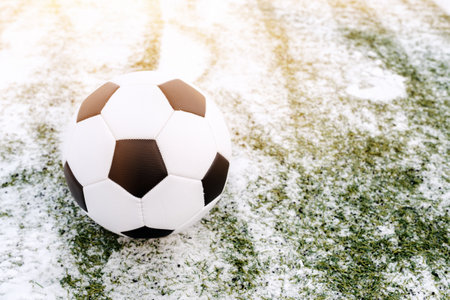 Soccer ball placed on snowy grass in winter on sports ground, copy spaceの写真素材