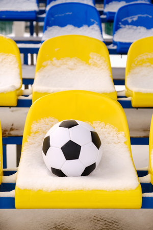 Soccer ball placed on snowy seats on stadium tribune in winter. Vertical orientationの写真素材