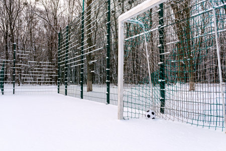 Soccer ball placed in corner of goal on snowy sports ground in winterの写真素材