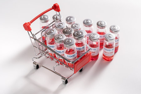 Wire shopping cart with vaccine vials bottles for vaccination against  pandemic on white background, sale of vaccinesの写真素材