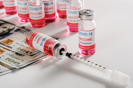 new vaccine with dollar bills and filling syringe on white backgroundの写真素材