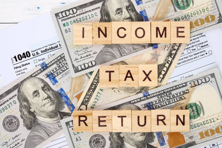 Words income tax return, form 1040 and dollar bills. Tax payment and filing concept.の写真素材