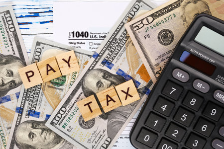 Words pay tax on form 1040, dollar bills and calculator. Tax payment and filing concept.の写真素材