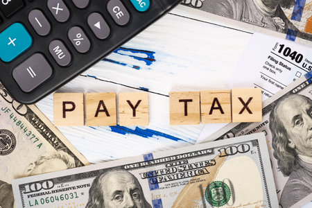 Words pay tax on form 1040, dollar bills and calculator. Tax payment and filing concept. Top view, flat layの写真素材