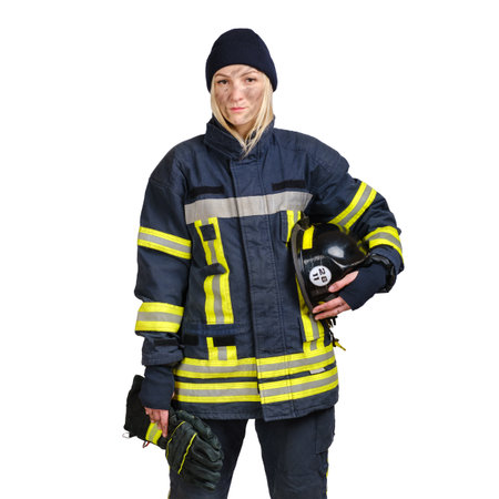 Young brave woman with dirty face in uniform of firefighter holds hardhat and gloves in hand and looking at camera isolated on white background. Copy space for textの写真素材