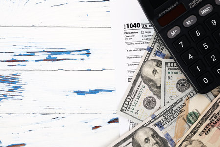 Personal income tax form 1040, dollar bills and calculator. Tax payment and filing concept, copy space, top viewの写真素材