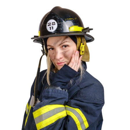Portrait of young brave woman in uniform of firefighter and hardhat touching face with hand and looking at camera isolated on white gray backgroundの写真素材