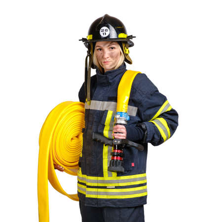 Young brave woman in uniform and hardhat of firefighter with fire hose on shoulders looking at camera on white background.の写真素材