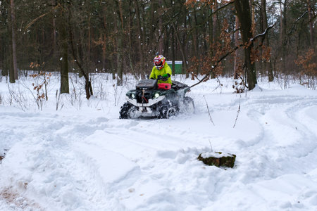 KYIV, UKRAINE - FEBRUARY 21: A man rides a quad bike in a snowy winter park. Seasonal leisure...