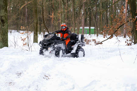 KYIV, UKRAINE - FEBRUARY 21, 2021: A man rides a quad bike in a snowy winter park. Seasonal leisure conceptのeditorial素材
