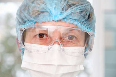 Close-up of the doctors tired eyes through protective glassesの写真素材