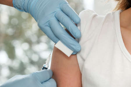 Doctor hands in protective gloves making vaccination in the shoulder of patient close-up. Vaccination against coronavirus COVID19の写真素材