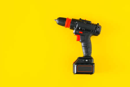 Handheld cordless power drill, hand battery screwdriver on yellow background. Top view, copy spaceの写真素材