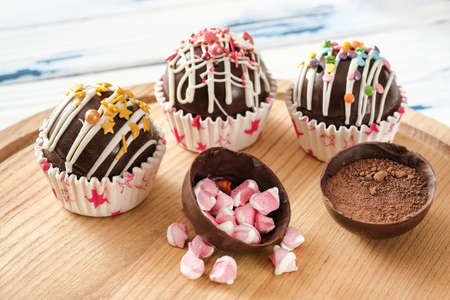 Cocoa bombs are black chocolate shells filled with cocoa powder and marshmallows that melt when hot milk is added, open in a mug and create a trendy delicious drink. Selective focusの写真素材